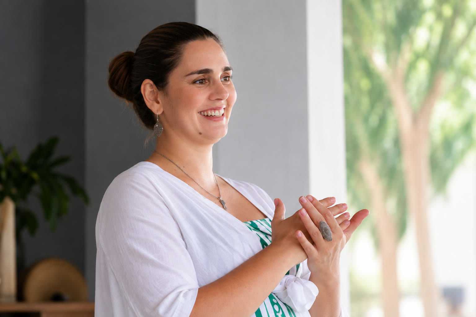 Elô sorrindo, com as mãos unidas, durante um encontro